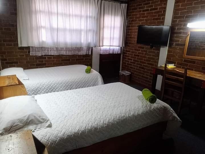 a room with two beds and a flat screen tv at Hotel Real del Campo in Quetzaltenango