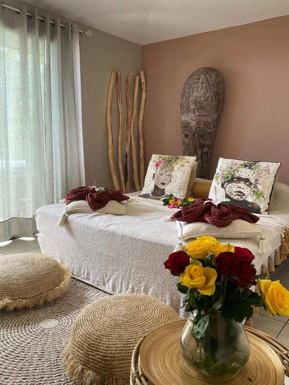 um quarto com duas camas e um vaso de flores sobre uma mesa em RICA RESIDENCE em Dumbéa