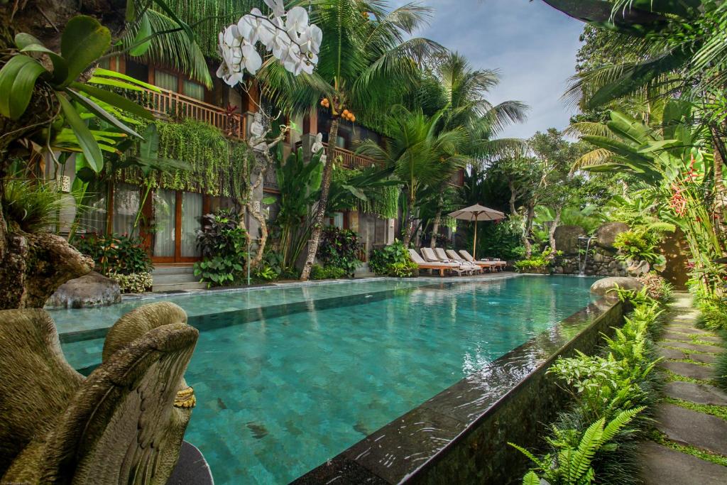 a pool at a resort with chairs and palm trees at Weda Cita Resort and Spa by Mahaputra in Ubud