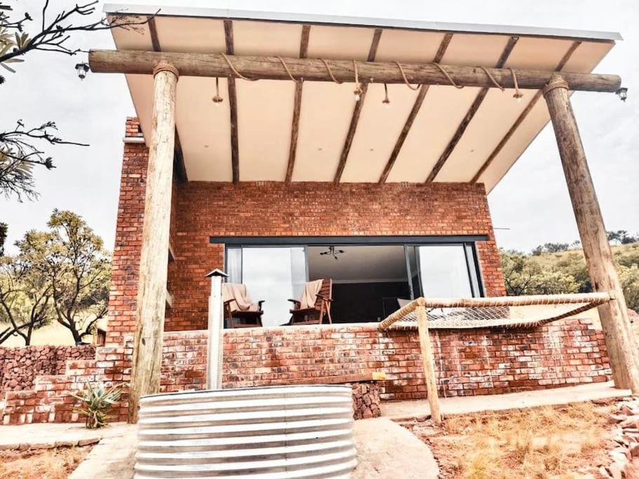 a brick house with a porch and a window at Rocky Road Mountain Lodge in Pretoria