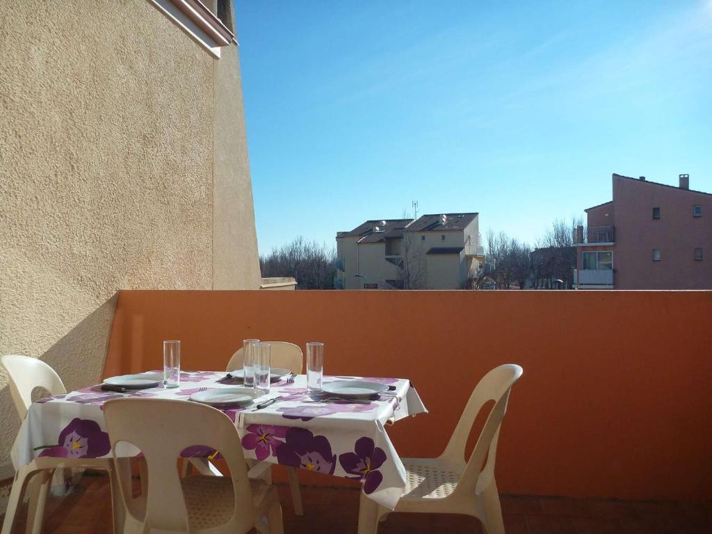 - une table avec des chaises blanches et une table avec des verres à vin dans l'établissement Appartement proche plage avec terrasse, 6 couchages, parking privé, Internet optionnel - FR-1-387-75, à Marseillan