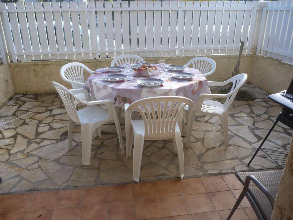 une table blanche avec des chaises blanches, une table et des chaises dans l'établissement Appartement 6 pers, terrasse, à 2 pas de plage et commerces, parking, option Internet - FR-1-387-153, à Marseillan