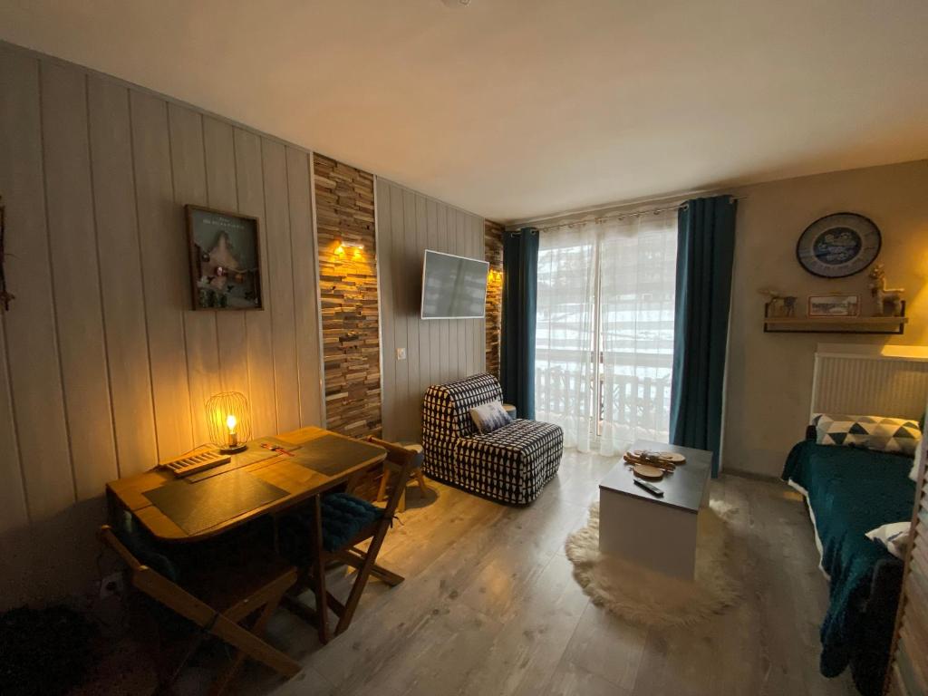 uma sala de estar com uma mesa e uma cadeira em STUDIO COCOONING SUPERDEVOLUY PIED DES PISTES em Le Dévoluy