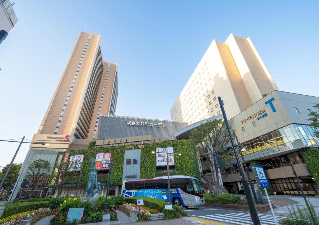 a bus is parked in front of two tall buildings at Ours Inn Hankyu in Tokyo