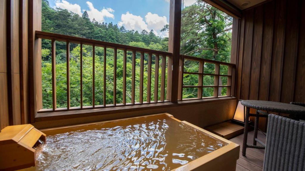 a hot tub in a room with a large window at Shionoyu Onsen Rengetsu in Nasushiobara