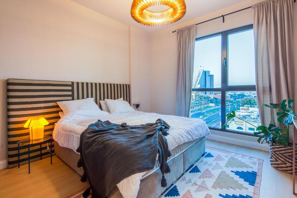 a bedroom with a bed and a large window at Burj Al Arab View - 1BR in MJL Lamtara 1- Sea View 703 in Dubai