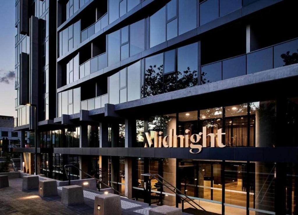 a large glass building with a midnight sign on it at 2 Bed 2 Bath Luxury Apartment in Braddon Canberra - Free heated pool, gym, parking in Canberra