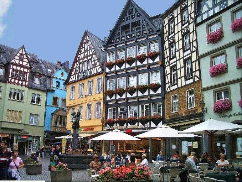 een groep mensen die aan tafels voor gebouwen zitten bij Wohnen über den Dächern der Cochemer Altstadt in Cochem