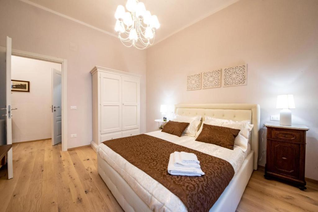 - une chambre avec un grand lit et un lustre dans l'établissement Residenza Vicolo Bovi Assisi, à Assise