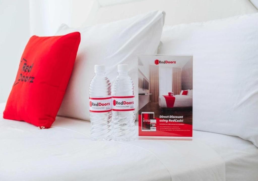 due bottiglie d'acqua sedute su un letto accanto a un libro di RedDoorz @ Leoncia Apartelle Mandaue City a Mandaue