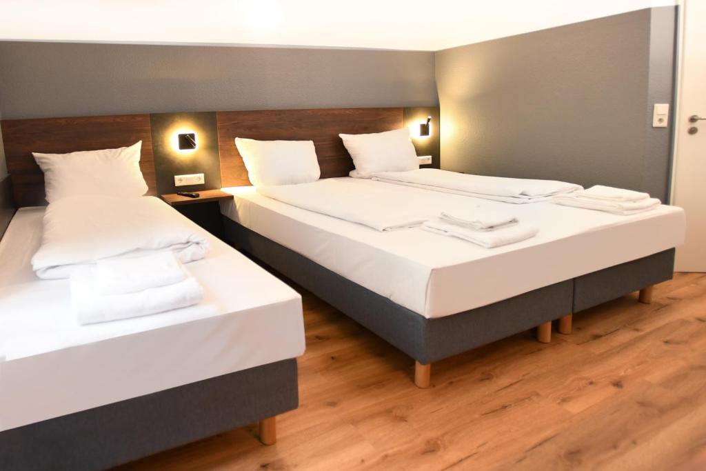 2 Betten in einem Hotelzimmer mit weißer Bettwäsche in der Unterkunft Hotel Apadana Frankfurt in Frankfurt am Main