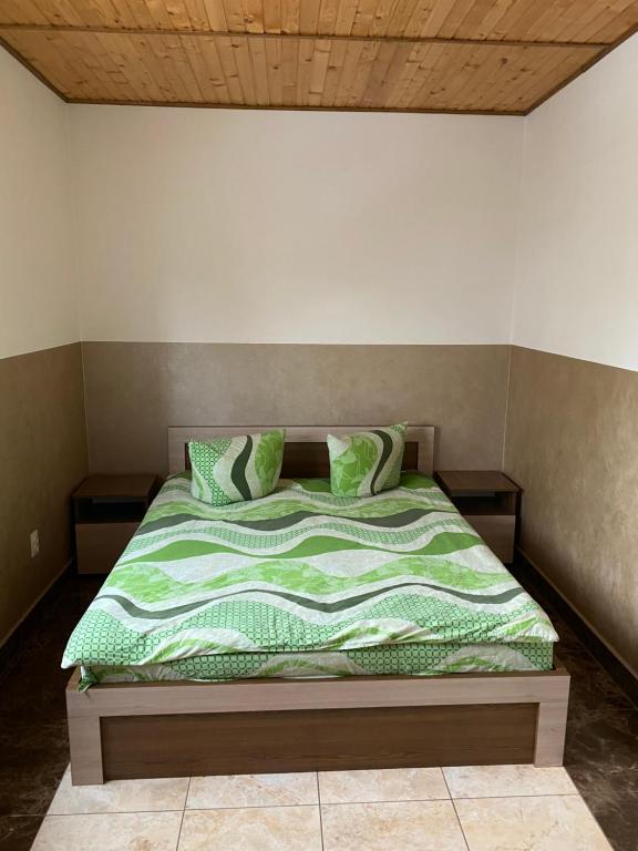 een bed met groene lakens en kussens in een kamer bij Домашній Затишок in Stryi