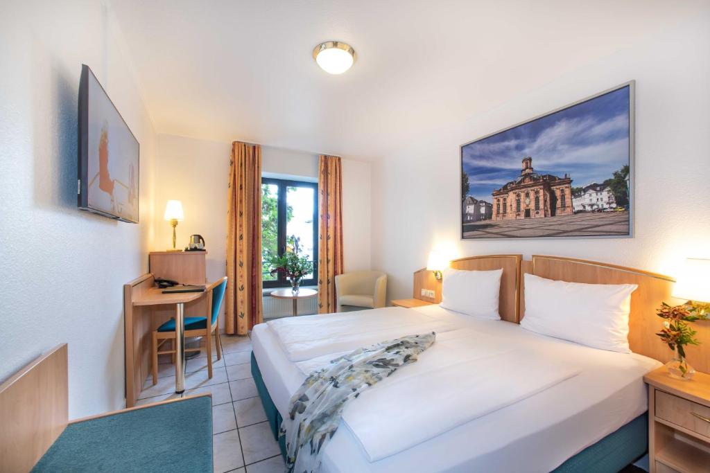 Cette chambre comprend un lit et un bureau. dans l'établissement UNO Hotel Posthof Saarlouis, à Sarrelouis