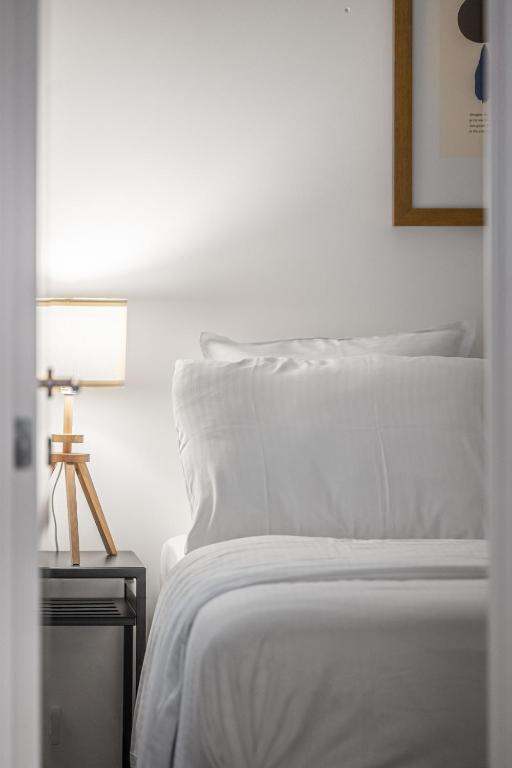 a bed with white sheets and a lamp on a table at Milano Ostend - Casselbergh Residences in Ostend