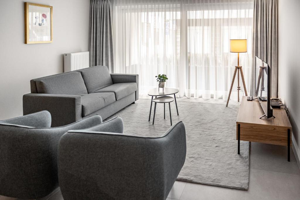 een woonkamer met een bank, stoelen en een tafel bij Casselbergh Residences Milano - Oostende in Oostende