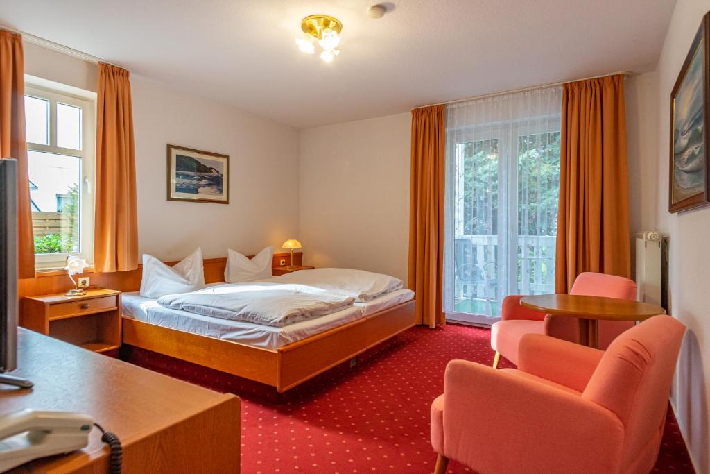 a hotel room with a bed and two chairs at Pension Bergen in Bergen auf Rügen