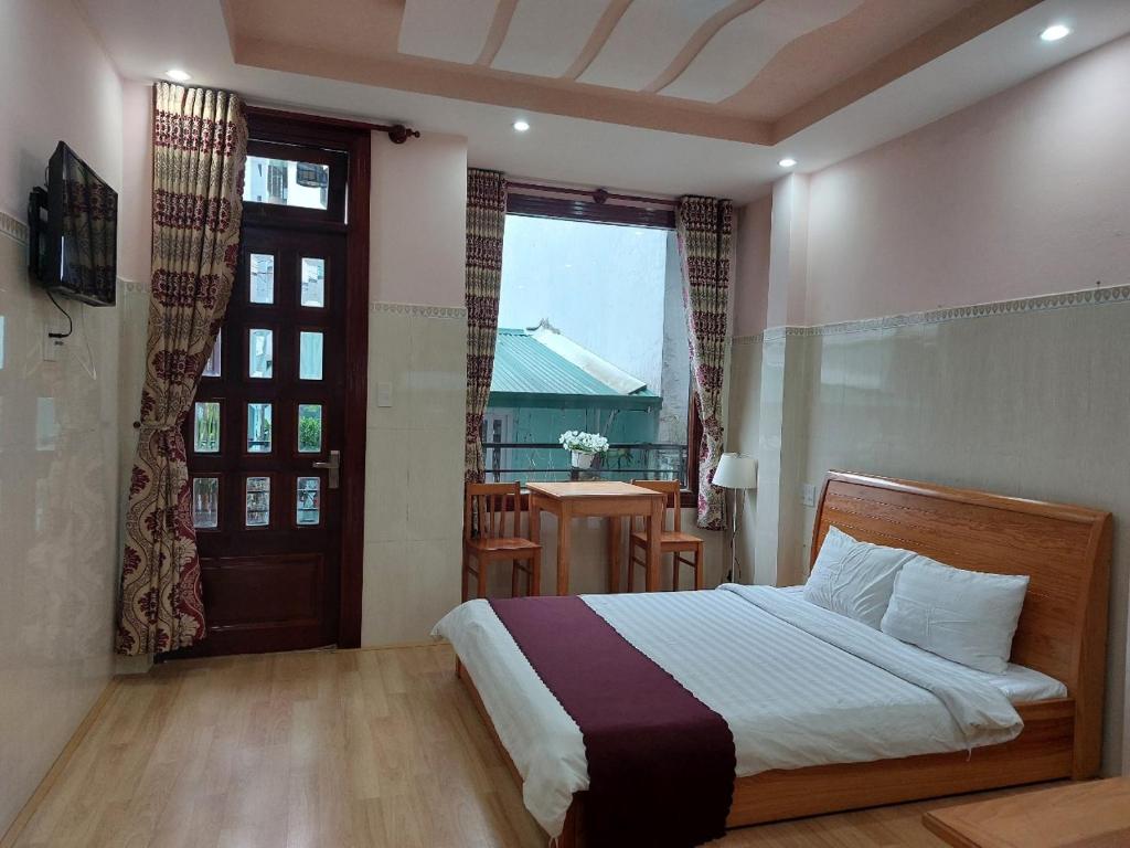 a bedroom with a bed and a window and a door at New Sleep in Dalat Hostel in Da Lat