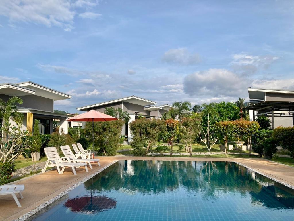 Oneandaman Resort في خاو لاك: مسبح مع كرسيين ومنزل
