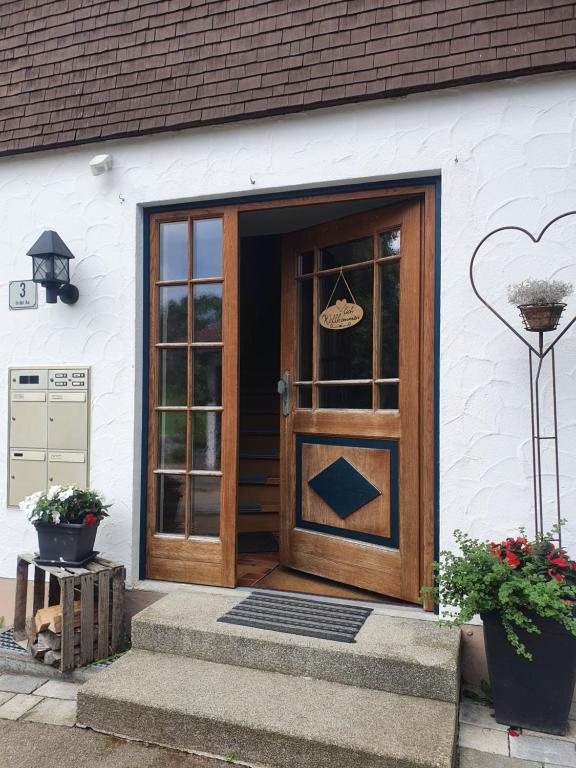 drewniane drzwi na białym budynku z roślinami w obiekcie FeWo Stegenbach Oberstaufen/Steibis w mieście Oberstaufen