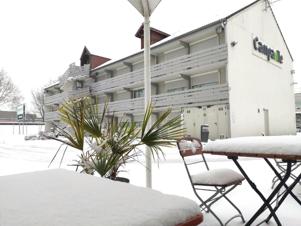 a snow covered building with two chairs in front of it at Campanile Chambéry in Chambéry