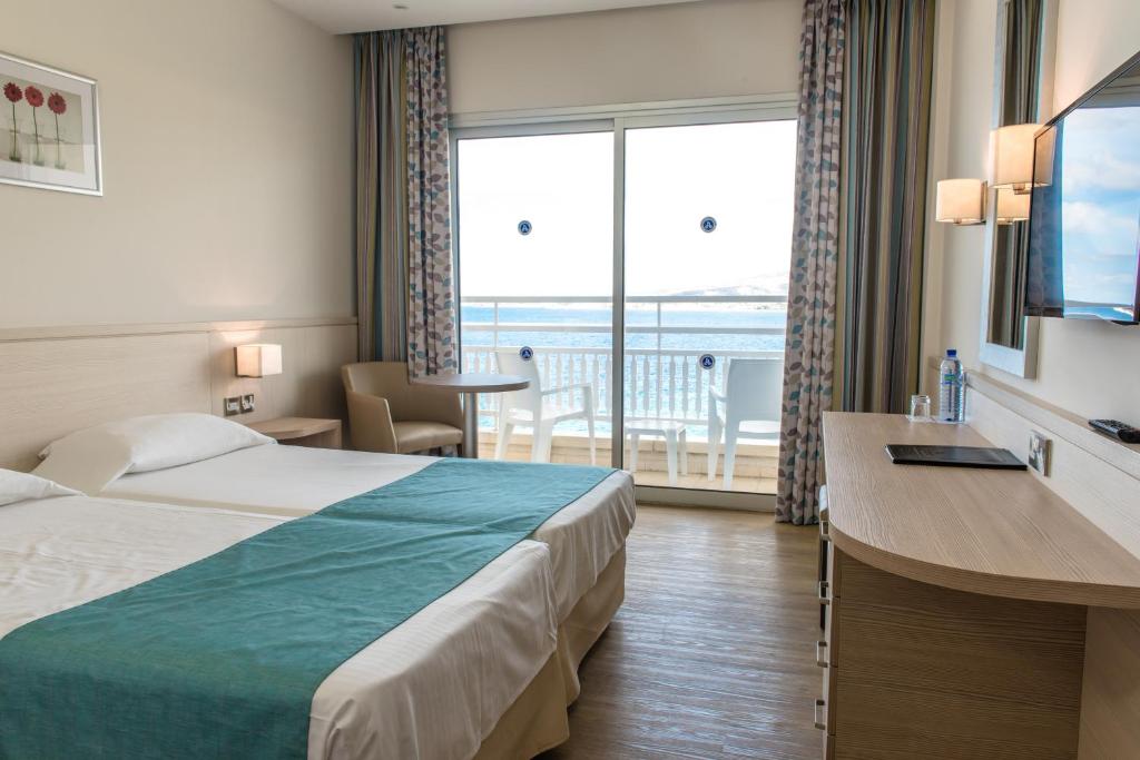 a hotel room with a bed and a large window at Cynthiana Beach Hotel in Paphos City