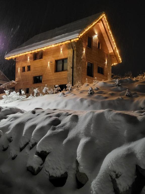 a log cabin in the snow at night at Hillview Jasná Chalet in Belá