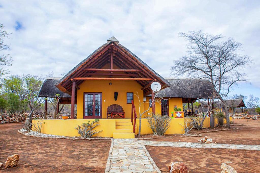 a small yellow house with a thatched roof at Luxe GAME-LODGE bordering Kruger in Phalaborwa