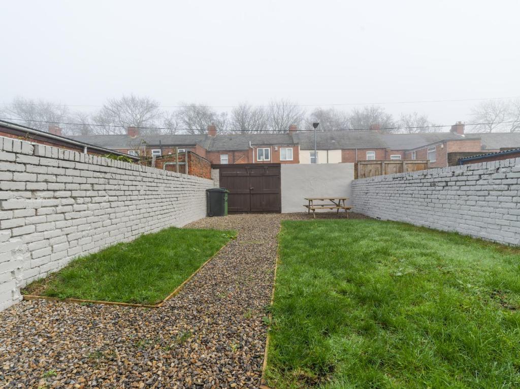 a brick wall with a bench in a yard at Hawthorn House - 2bedroom-Ashington Northumberland in Ashington