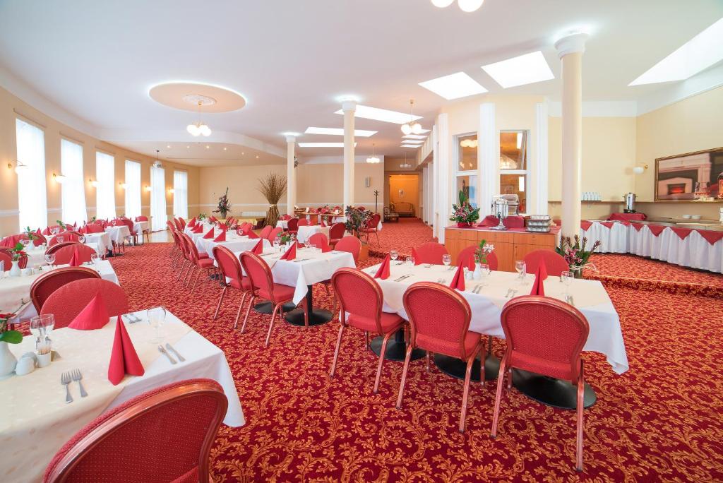 a banquet hall with white tables and red chairs at Spa Resort PAWLIK-AQUAFORUM in Františkovy Lázně