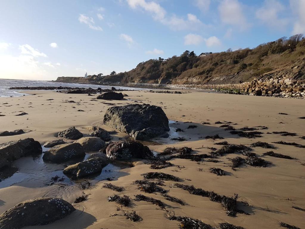 - une plage avec des rochers dans le sable et l'océan dans l'établissement Puckaster Cove Cabin, à Niton