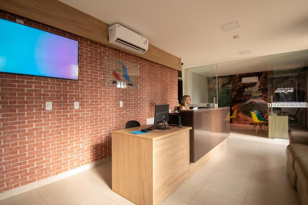 a woman sitting at a desk in an office at Hotel Araçás in Carolina