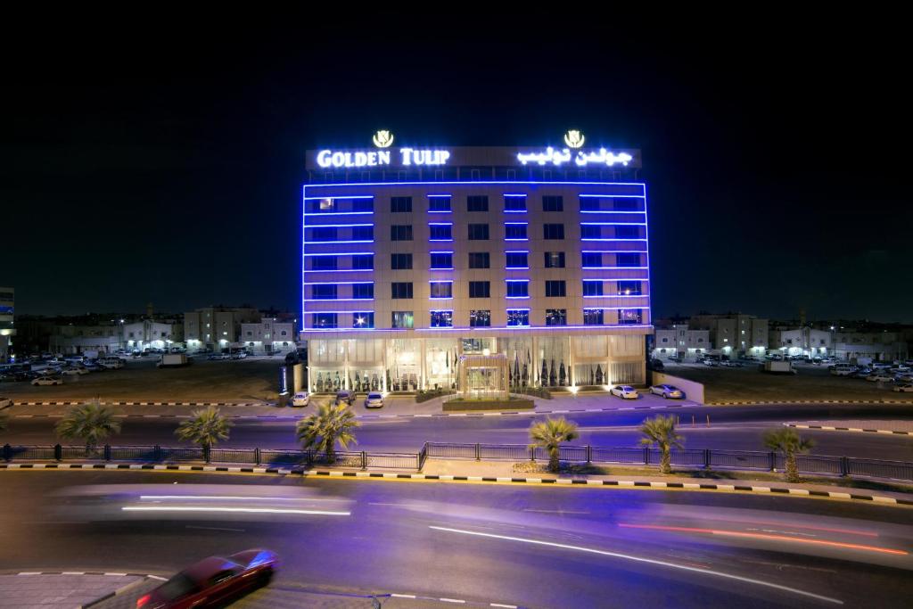 un edificio con un cartel encima por la noche en Golden Tulip Dammam Corniche Hotel, en Dammam