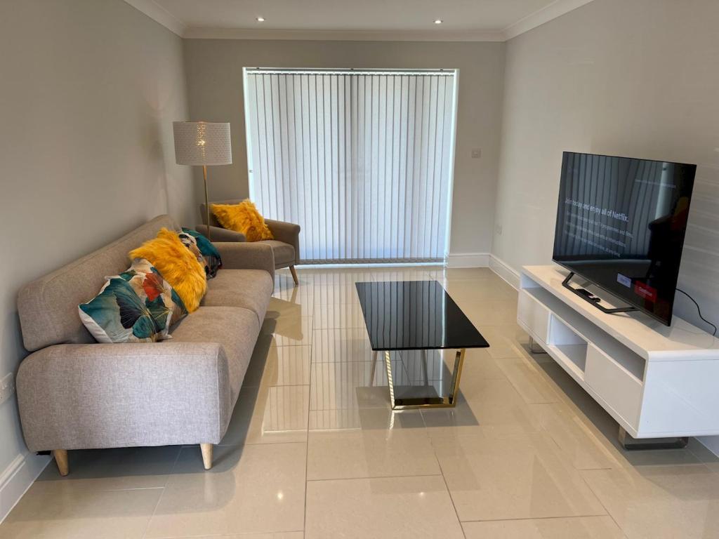 a living room with a couch and a flat screen tv at Pass the Keys Newly built house 4 mins from Twyford Centre in Reading
