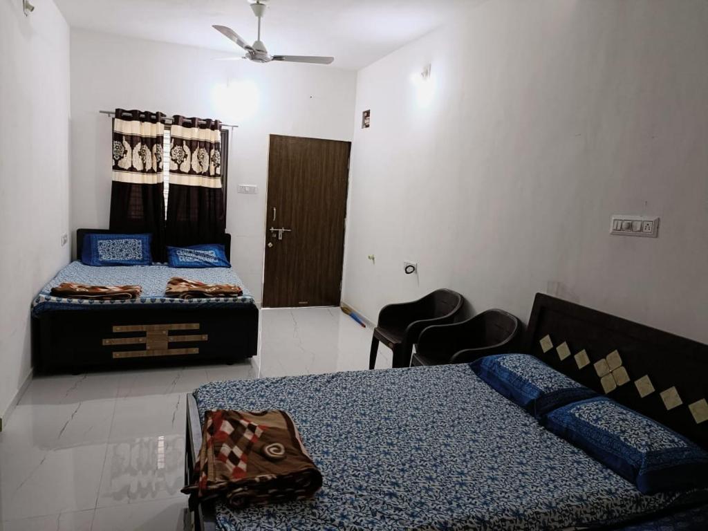 een slaapkamer met 2 bedden en 2 stoelen. bij Ekta Homestay in Garudeshwar