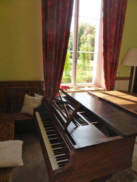 a piano sitting in a room with a window at Maison d&#39;hôtes Le Château de Puxe in Puxe