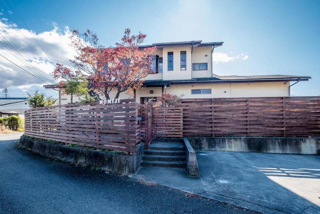 a fence in front of a house with a house at Engawa House Momiji-With hot spring in Fujikawaguchiko
