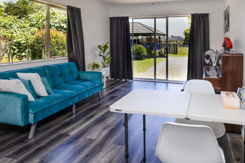 uma sala de estar com um sofá azul e uma mesa e cadeiras em Farm Stay on Te Awa Cycleway em Tamahere