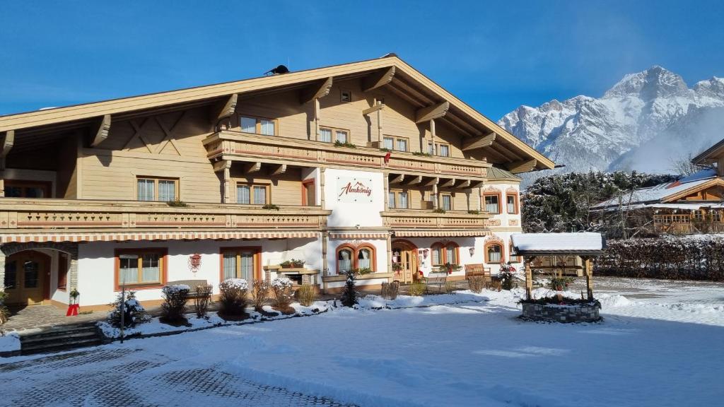 a large wooden building with snow on the ground at Almkönig in Maria Alm am Steinernen Meer