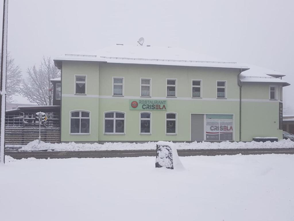 a white building with a sign on it in the snow at Ferienwohnung am Crisela in Ebersbach Sachsen