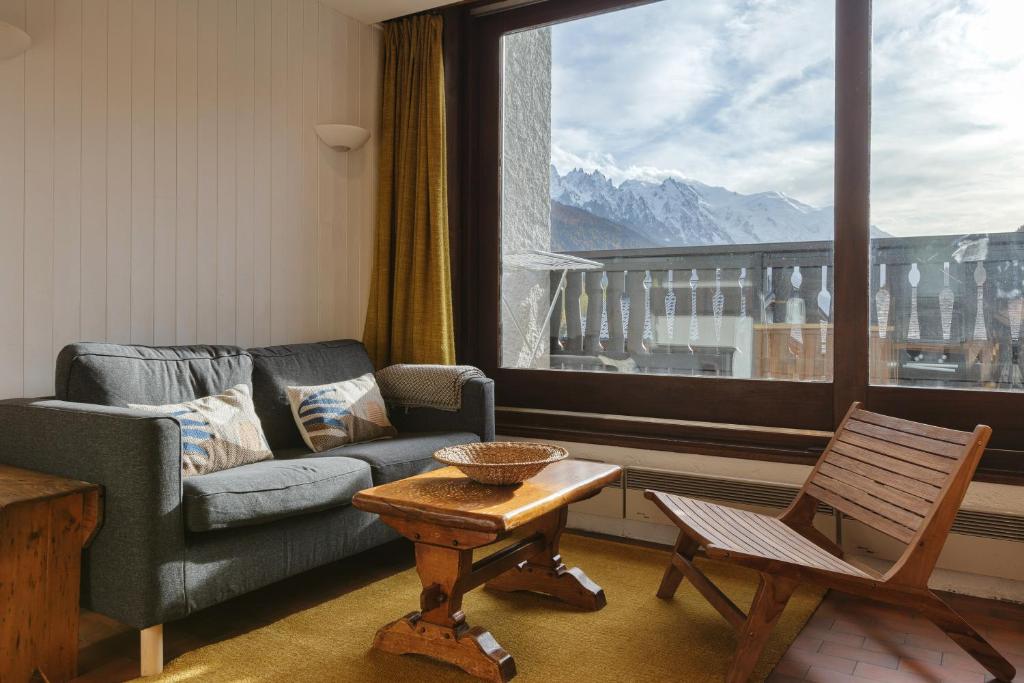 sala de estar con sofá, mesa y ventana en La Maison De Montroc - Happy Rentals, en Chamonix-Mont-Blanc