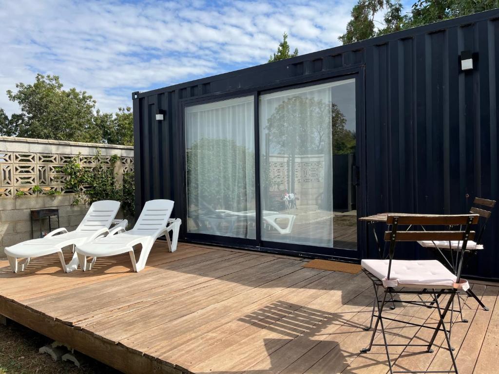 a black tiny house with white chairs on a deck at LA CASA CONTENEDOR in Zaragoza