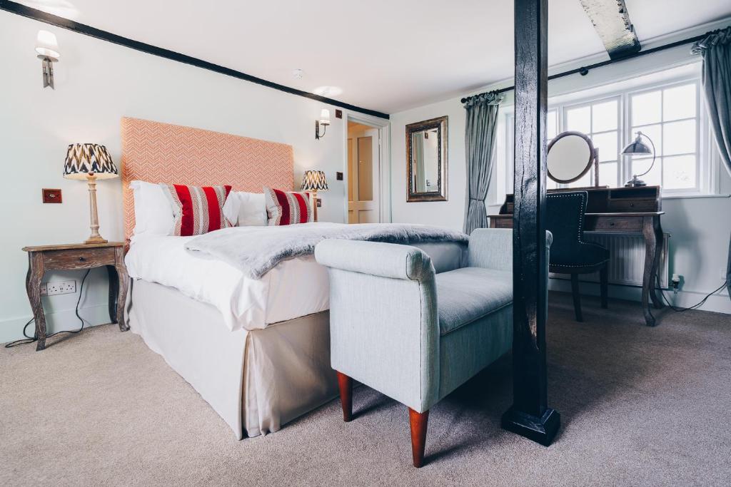 um quarto com uma cama, uma cadeira e um piano em The Crab & Lobster em Chichester