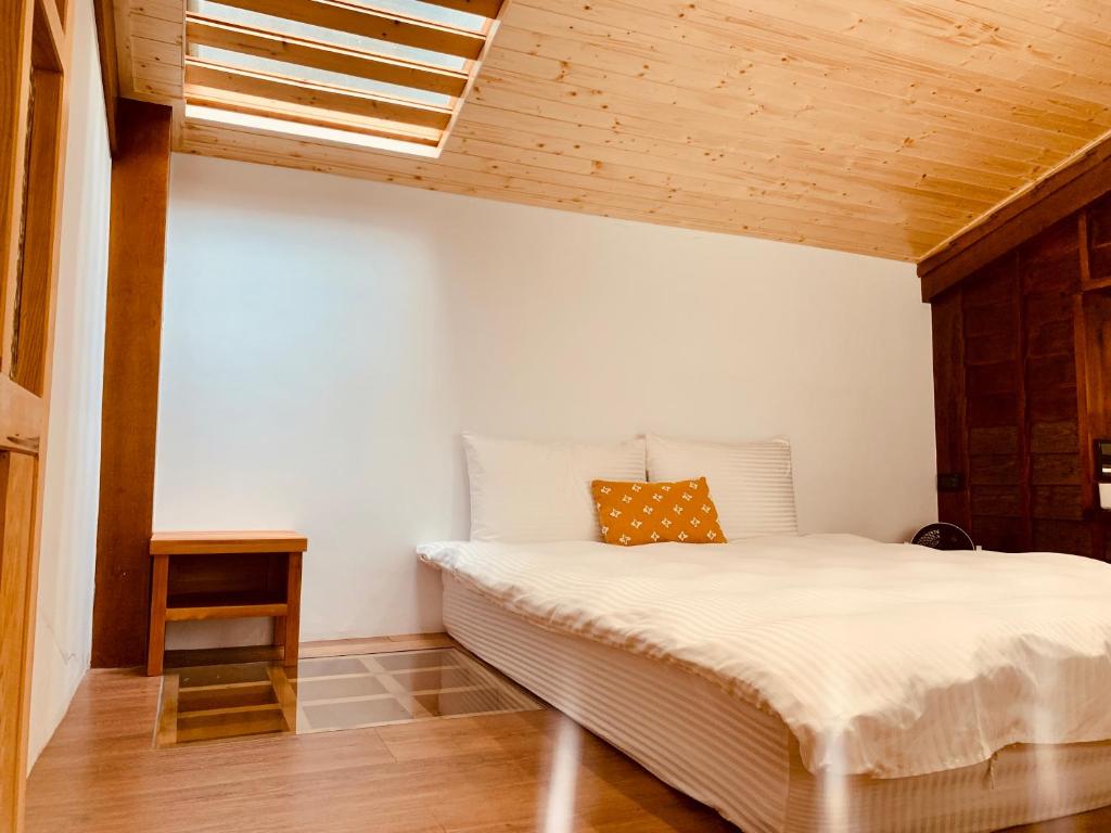 1 dormitorio con cama blanca y techo de madera en 末廣通一館 日式包棟民宿 Suehirodori Japanese Entire Homes No1, en Tainan