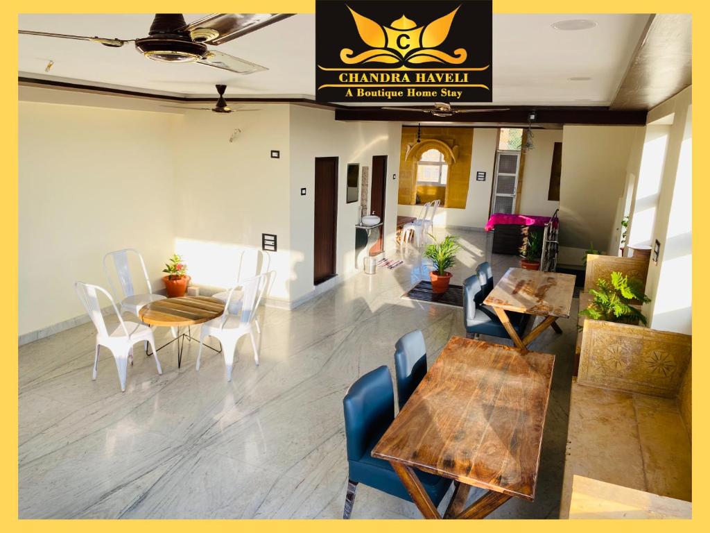 une salle à manger avec des tables, des chaises et un panneau dans l'établissement Chandra Haveli Boutique Homestay, à Jaisalmer