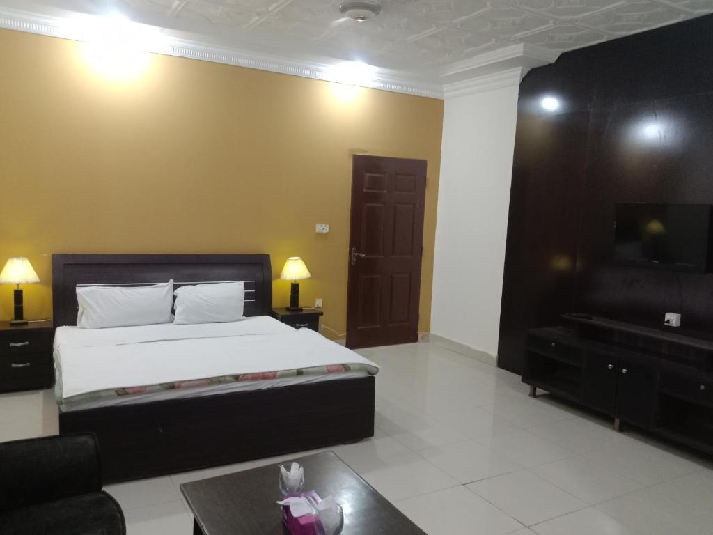 Victoria Guest House في بهاوالبور: غرفة نوم بسرير وتلفزيون بشاشة مسطحة