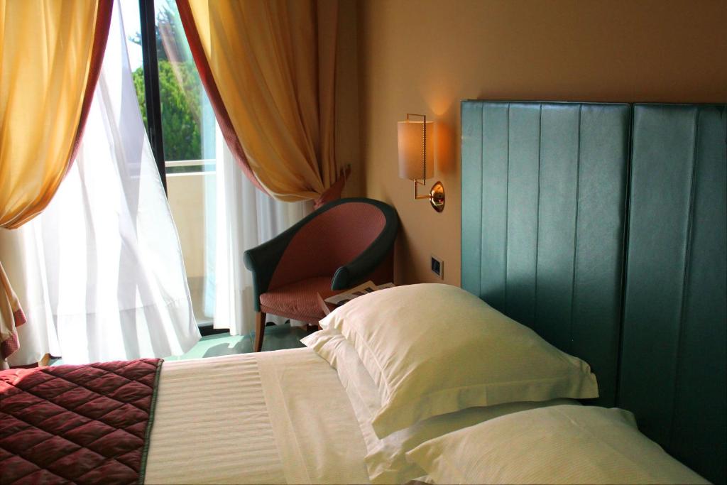 a bedroom with a bed and a chair next to a window at Hotel Cristallo in Giulianova