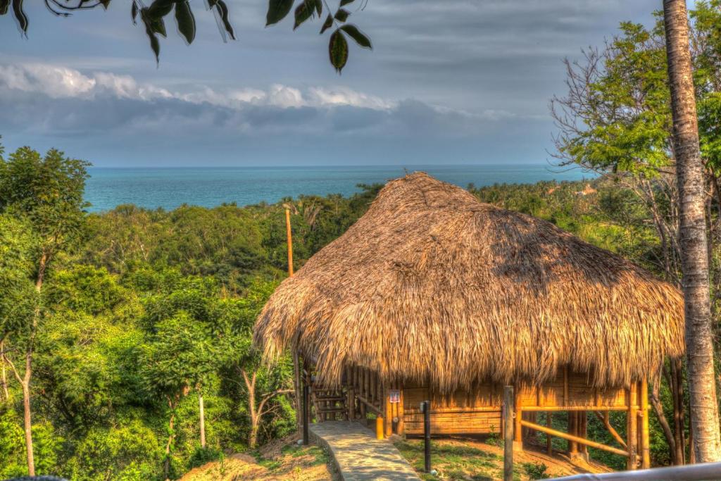 una cabaña con techo de paja y el océano en Villa Maria Tayrona, Jungle and Sea Experience, en Los Naranjos