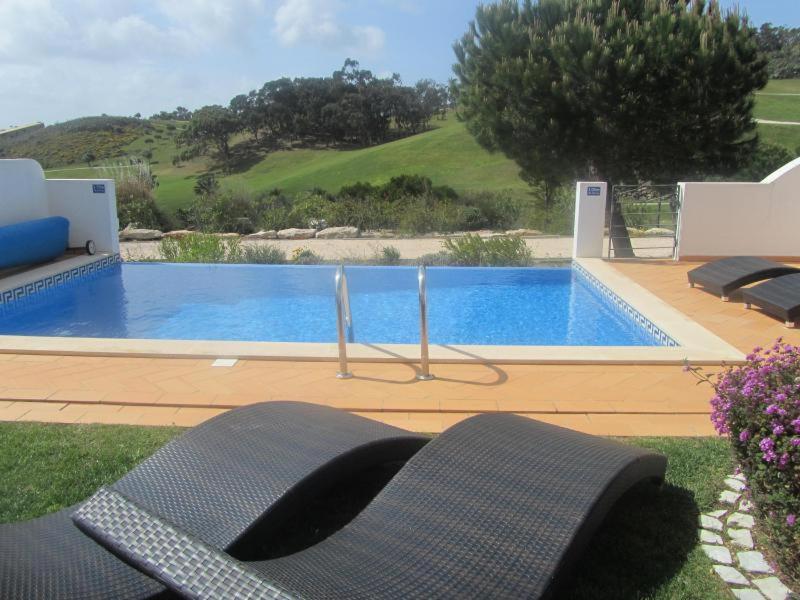 een zwembad in een tuin met twee stoelen ernaast bij Stunning 3 bed villa with pool- Golf Beach in Budens