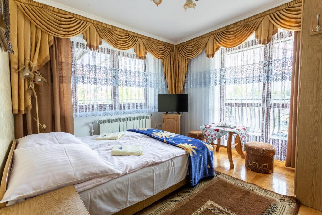 1 dormitorio con 1 cama con cortinas y TV en DW Paweł, en Zakopane