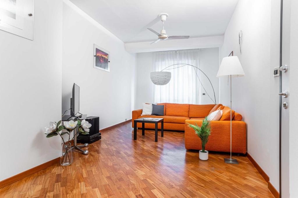 uma sala de estar com um sofá laranja e uma televisão em JOIVY Lovely and Inviting flat with balcony em Milão